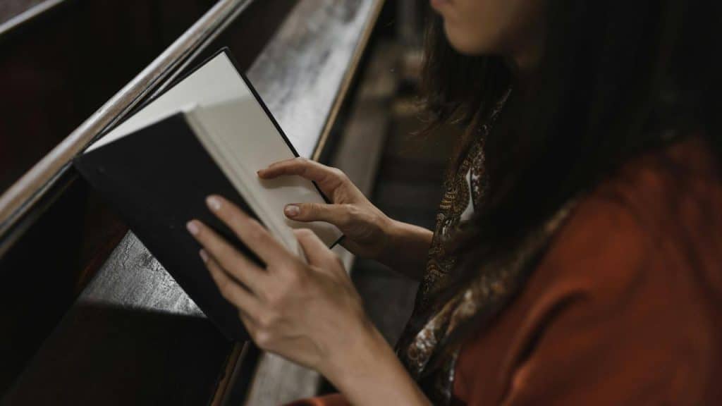 A woman sitting on a bench reading a book.