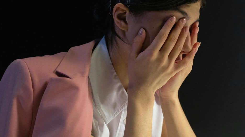 A woman covering her face with her hands in distress.