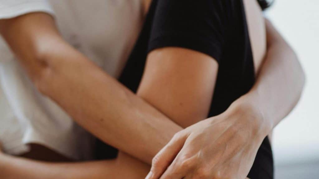 A close-up of two people embracing with their arms wrapped around each other.