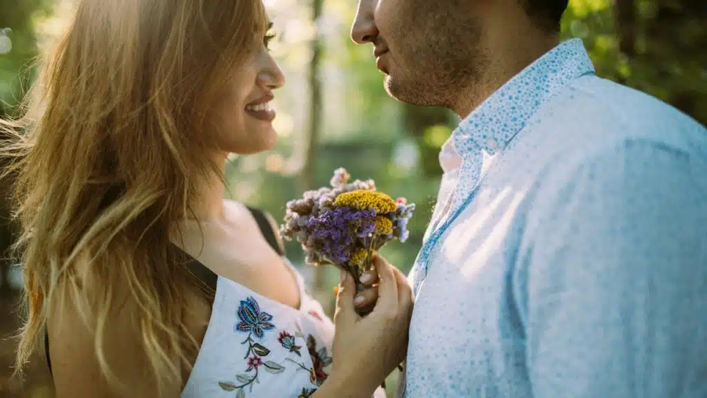 A man giving flowers to a woman standing next to him.