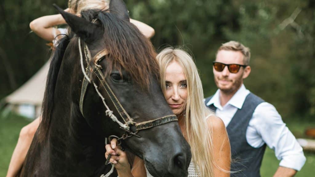 A couple walking while holding a horse with them.