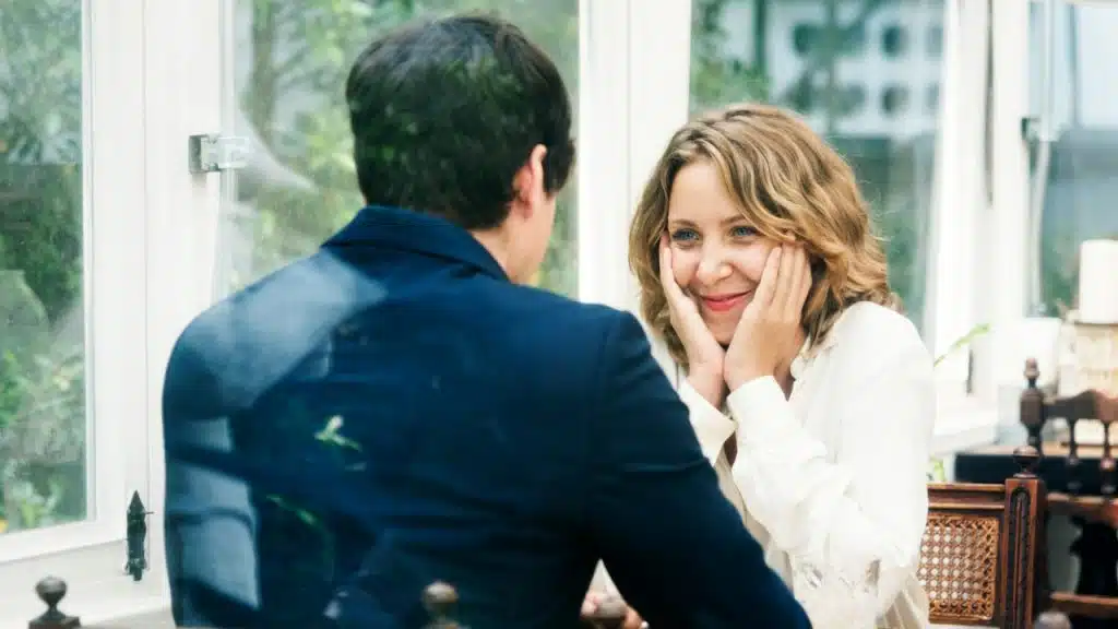 A woman holding her face in hands is listening intently to her husband while they are sitting together.