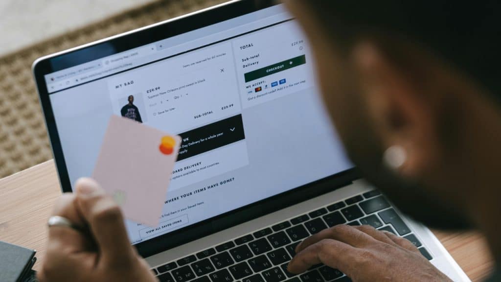 A person holds a card while looking at an online shopping checkout page on a laptop.