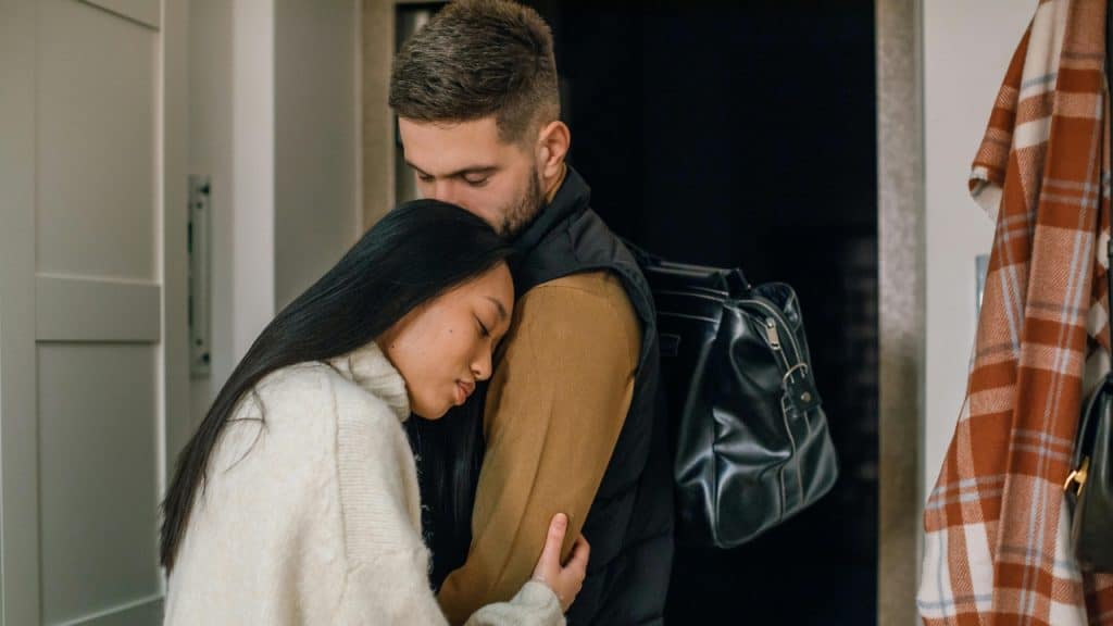 A woman rests her head on a man’s chest while he kisses the top of her head.