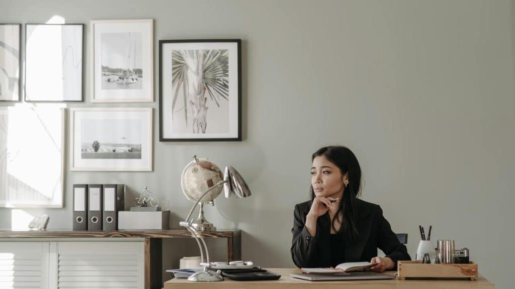 A woman sitting at a desk looking away in a modern office.