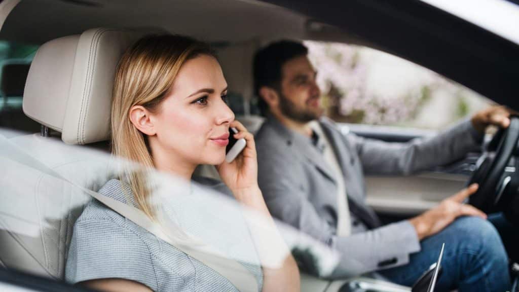 A woman talking on a phone while sitting in the passenger seat of a car.