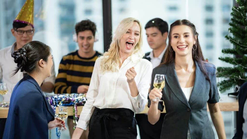 A group of people smiling and holding glasses of wine at a party with decorations.