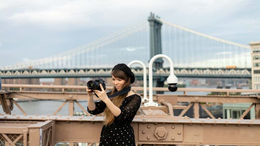 A woman taking a photo at the Brooklyn Bridge.