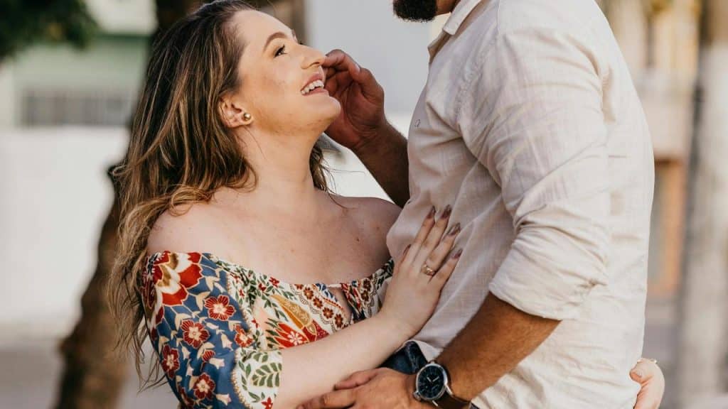 A woman smiling up at a man as they stand closely and touch affectionately.