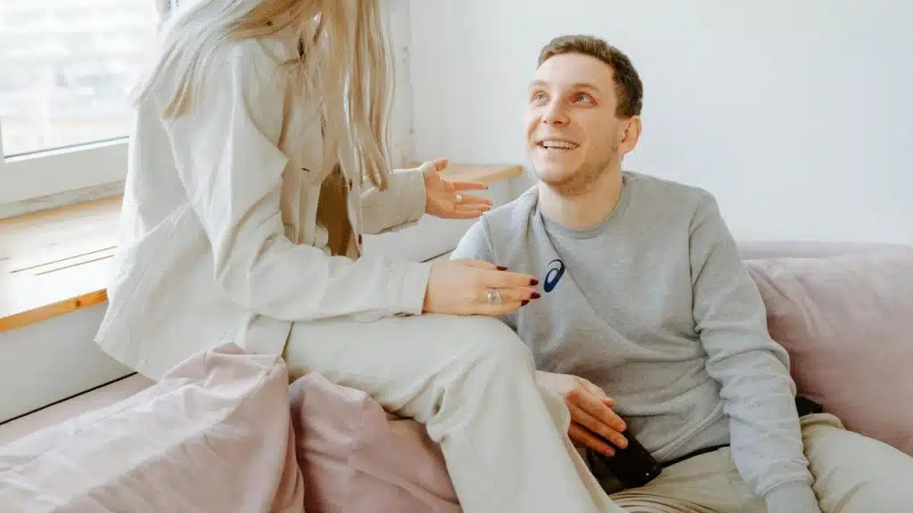A man smiling up at someone while sitting on a couch.