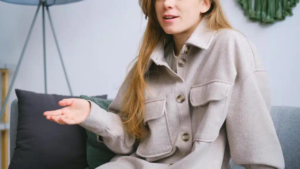 A woman sitting on a couch gesturing while talking.
