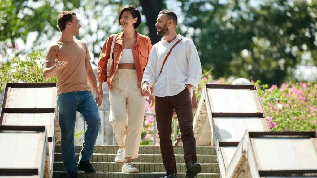 Three people walk down outdoor stairs together while smiling and talking to each other.