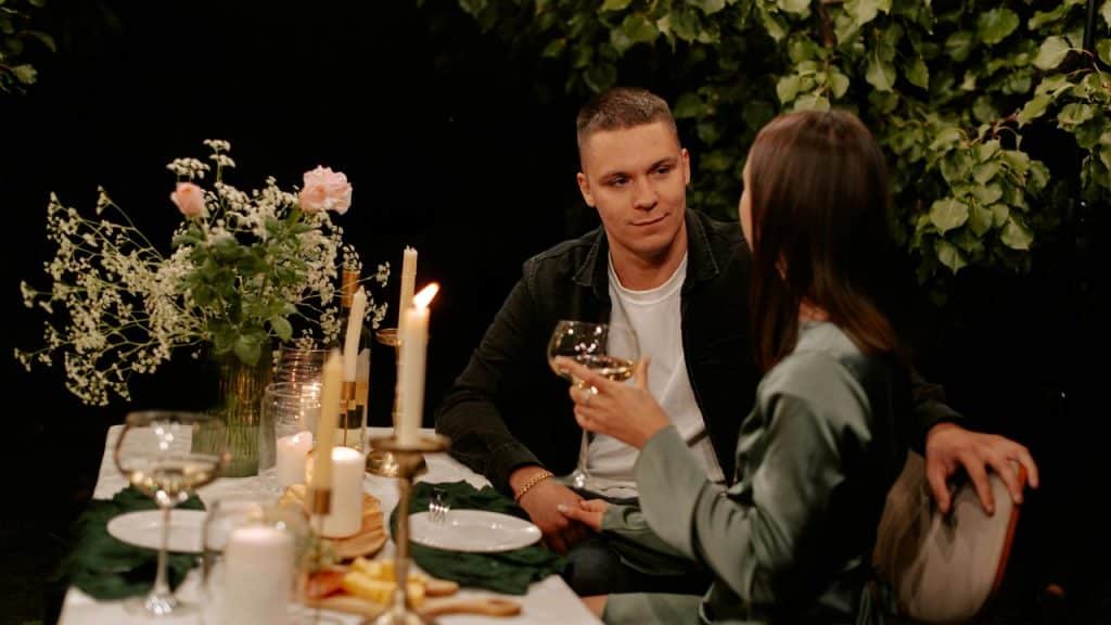 A couple enjoying a candlelit dinner and talking over wine.