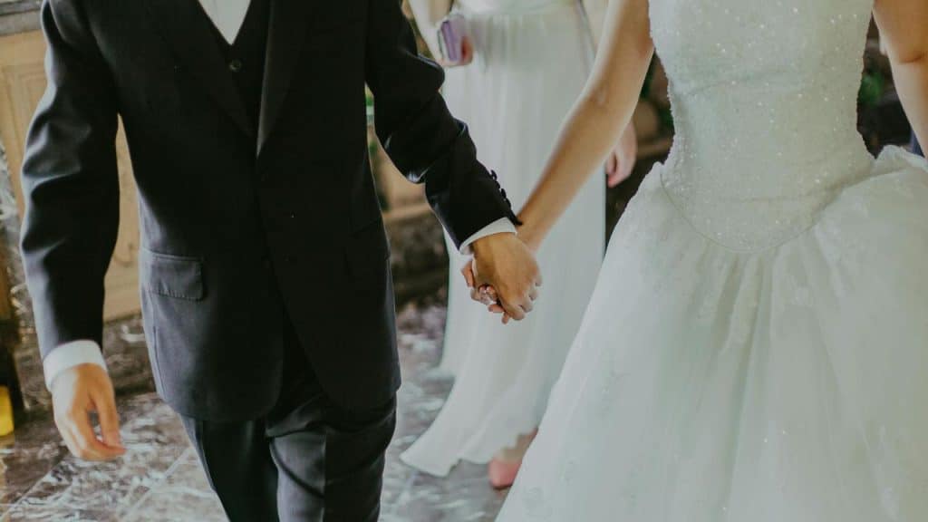 A bride and groom holding hands while walking together.