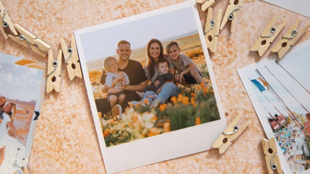 A printed photo of a family in a flower field is surrounded by wooden clothespins.