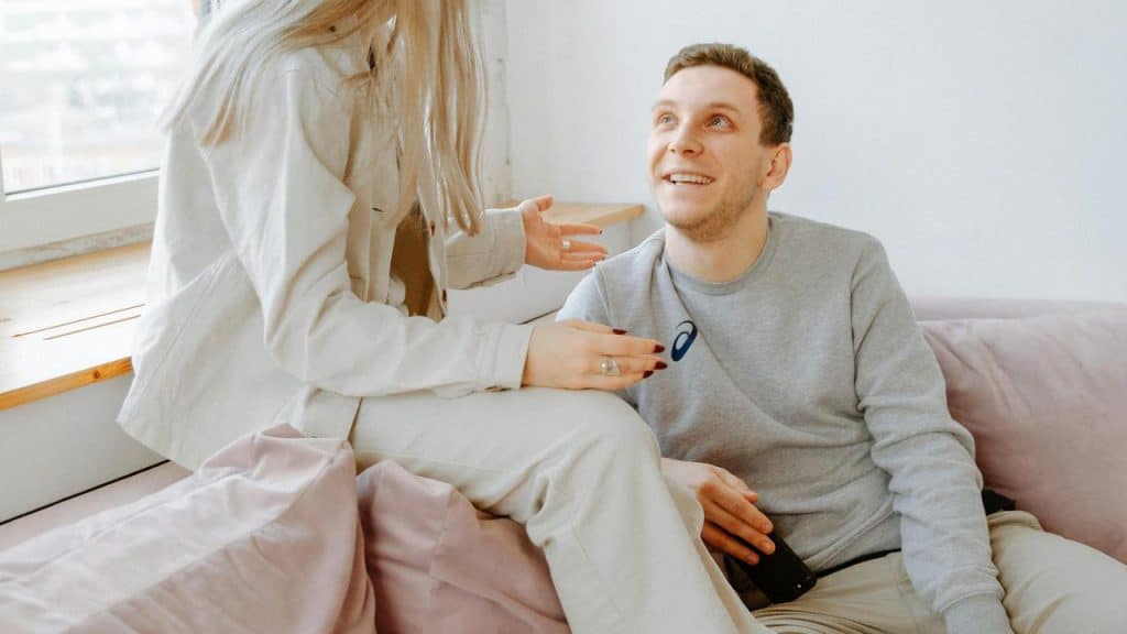 A man smiling up at a woman while sitting together on a couch.