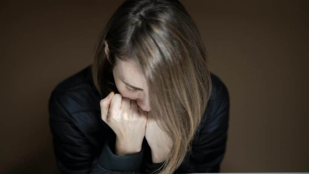 A young woman burying her face with her hands, conveying deep distress or sadness.
