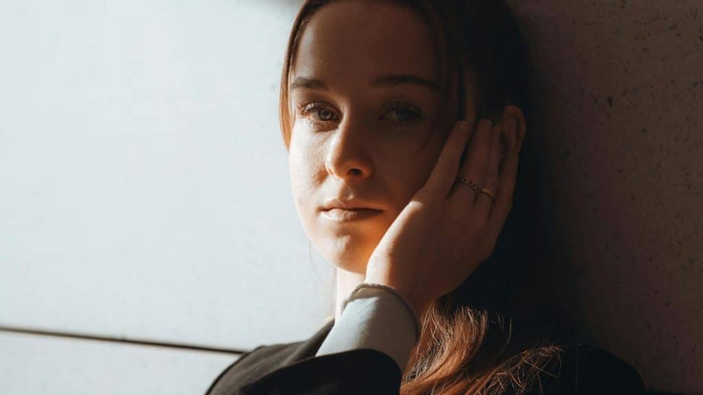 A woman resting her hand on her face while looking into the camera.