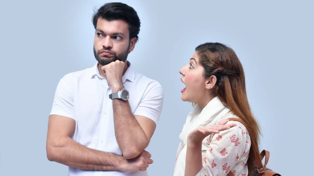 A woman shouting at her husband and the man is looking away.