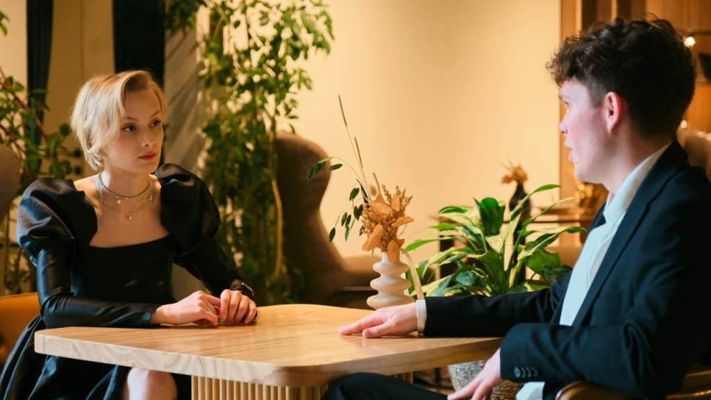 A man and woman sit across from each other at a wooden table in a restaurant.