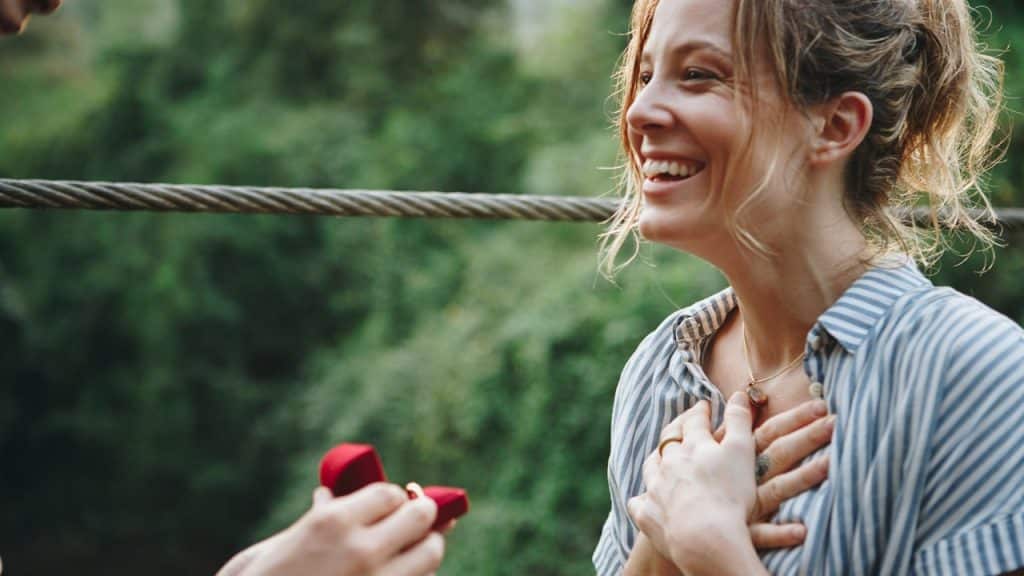 A man giving engagement ring to a woman standing in front of him.
