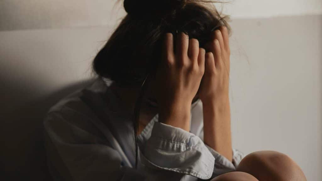 A woman sitting with her head in her hands looking overwhelmed.