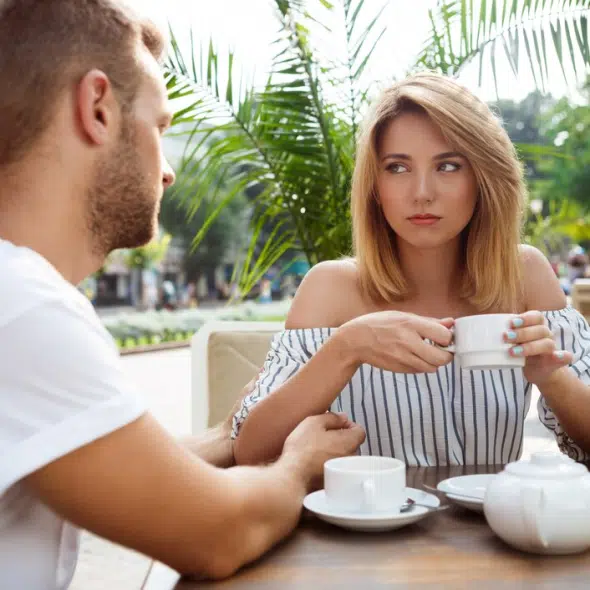 Young beautiful couple quarreling, sitting in cafe