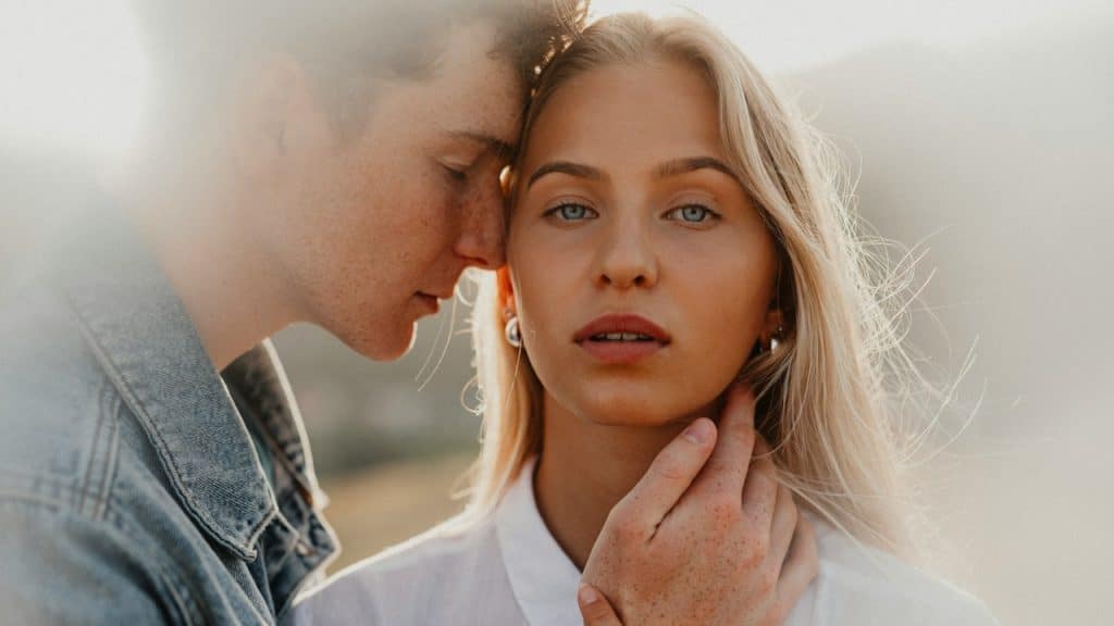 A man embracing his partner who is looking in the camera.