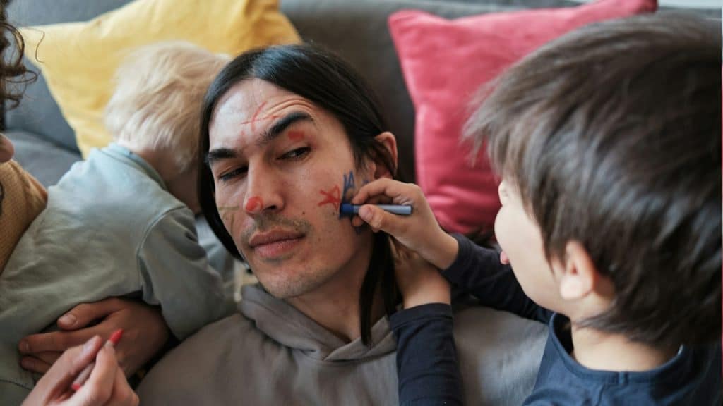 A kid making star on his father’s face.