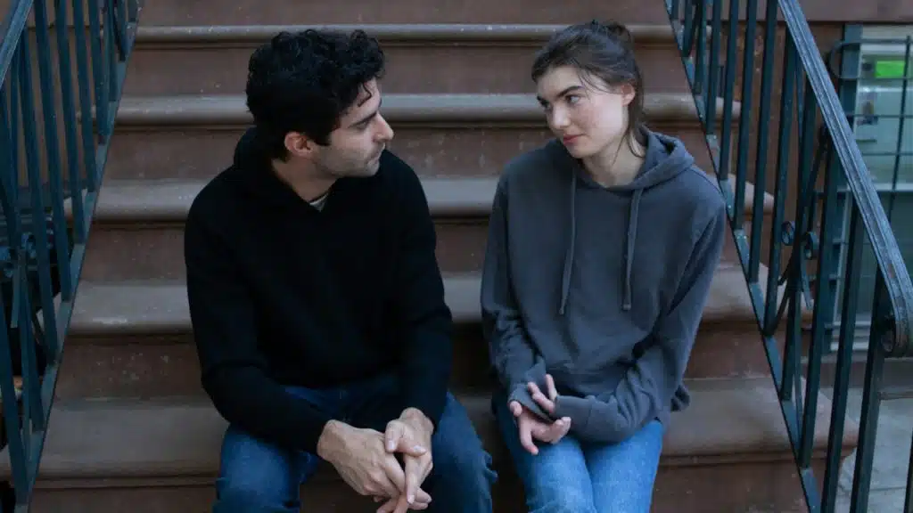 A man and a woman sitting on stairs looking at each other.