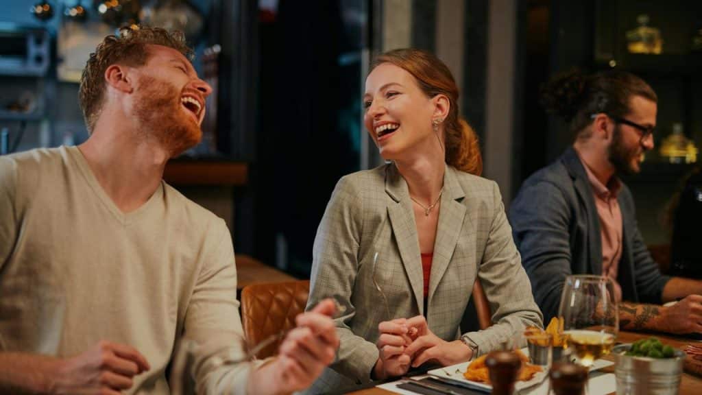A group of friends laughing together while dining at a restaurant.