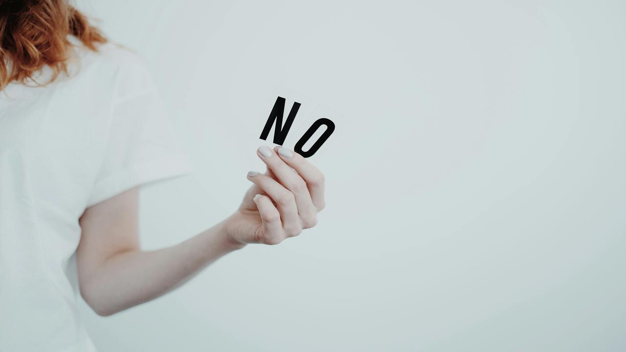 A woman holding letter spelling out “no”