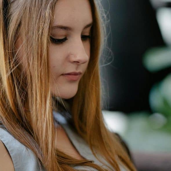 A young blonde woman looking down at her phone.