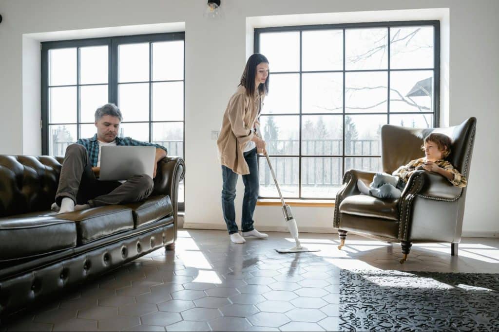 Woman cleaning and a man just letting her