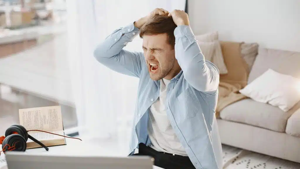 A man yelling and holding his head in frustration.