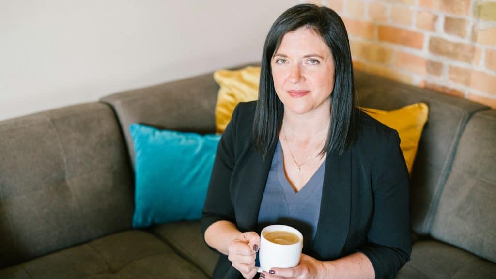 A woman sitting on a sofa and holding a mug.