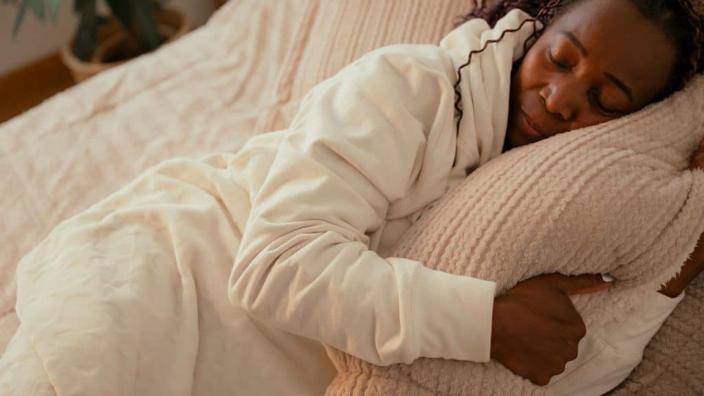 A woman sleeping peacefully while hugging a pillow in bed.