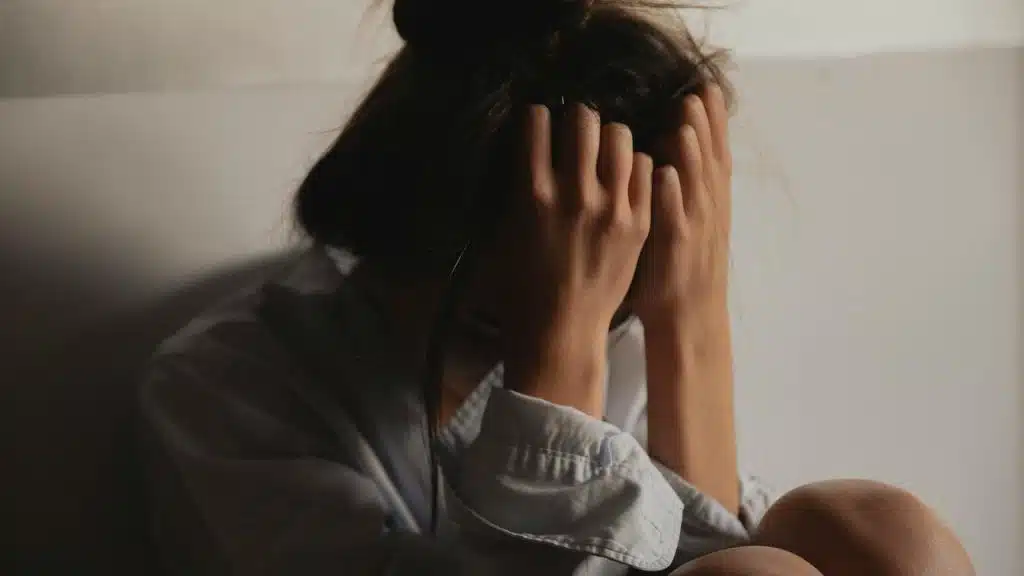 A woman sitting with her head in her hands looking distressed.