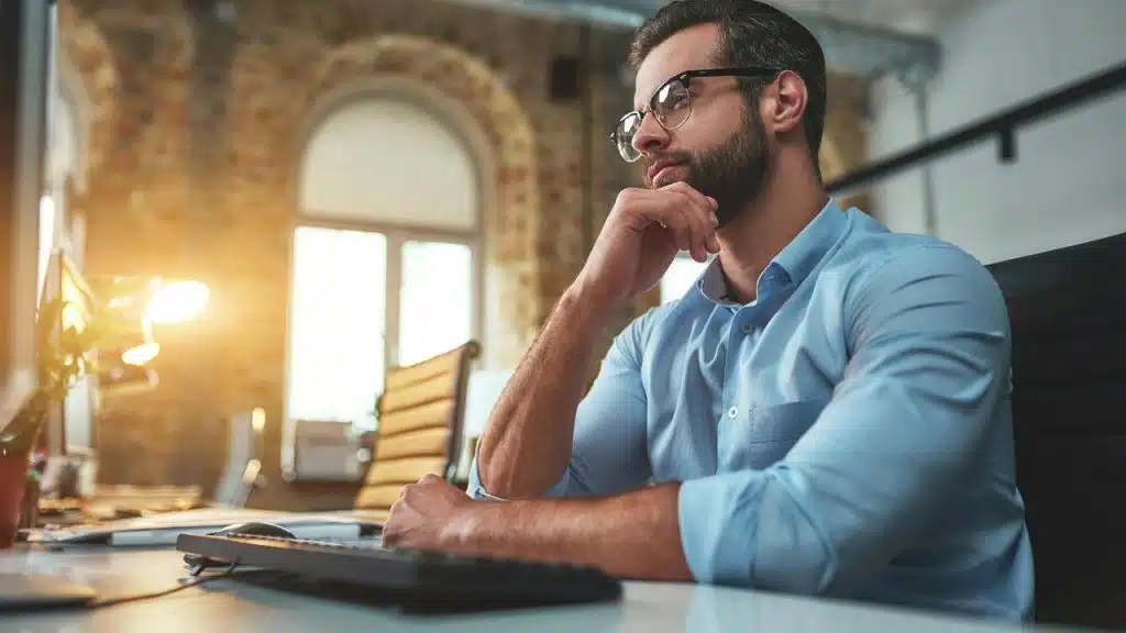 A man thinking at his desk in an office.