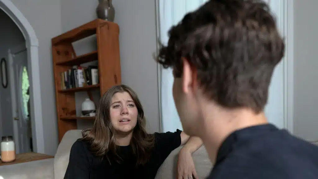 A woman complaining to her husband while sitting at a couch indoors,