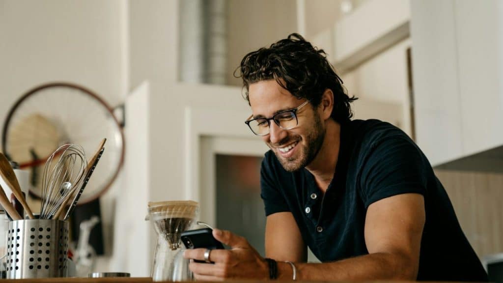 Two hands hold a smartphone displaying a red dating app interface with two user profiles.
