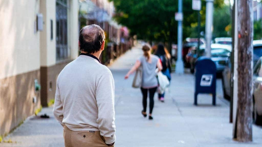 A man standing watching a woman going away.