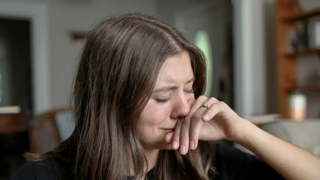 A crying woman wiping her nose with her hand.