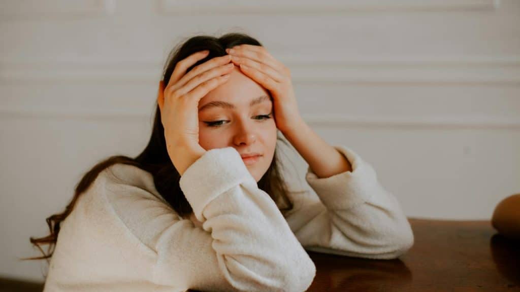 A woman resting her head in her hands while sitting at a table.