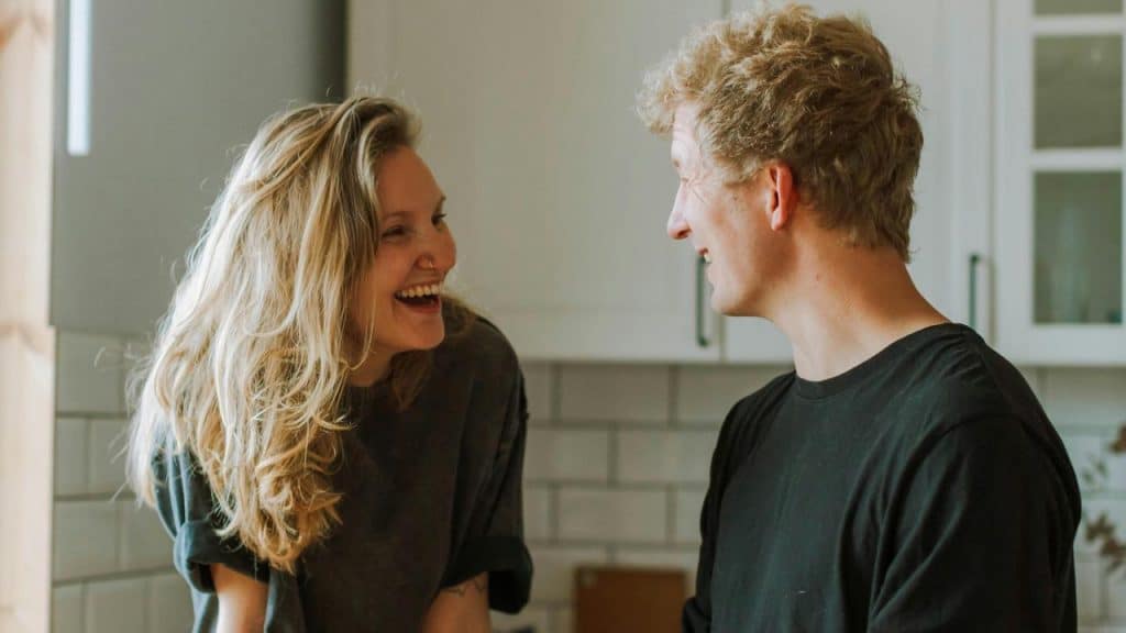 A smiling couple laughing together in a kitchen.