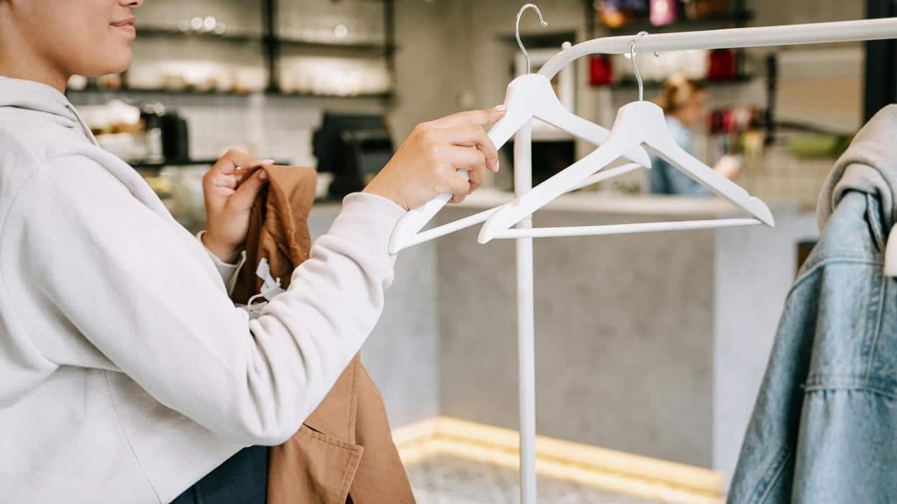 A person hanging clothes on a rack in a store or café.