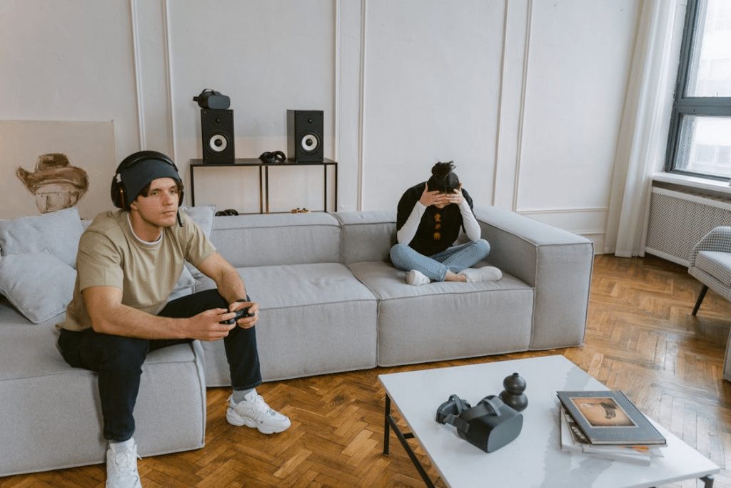 Man playing video games across couch from upset girlfriend