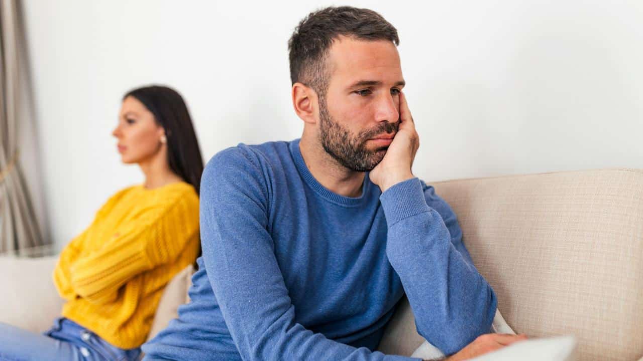 A young couple sitting on a couch after having argument