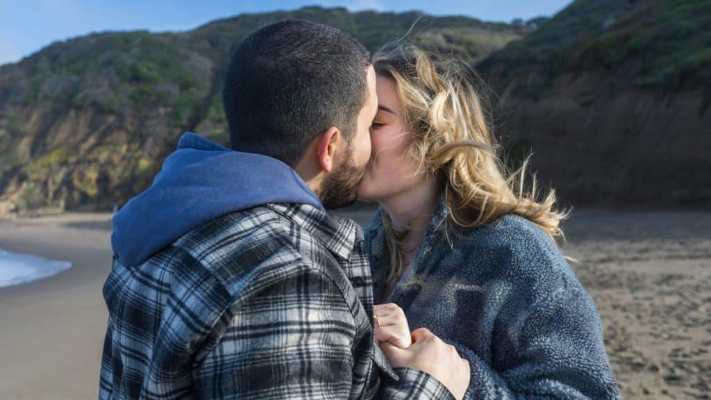 A couple kissing on a beach.