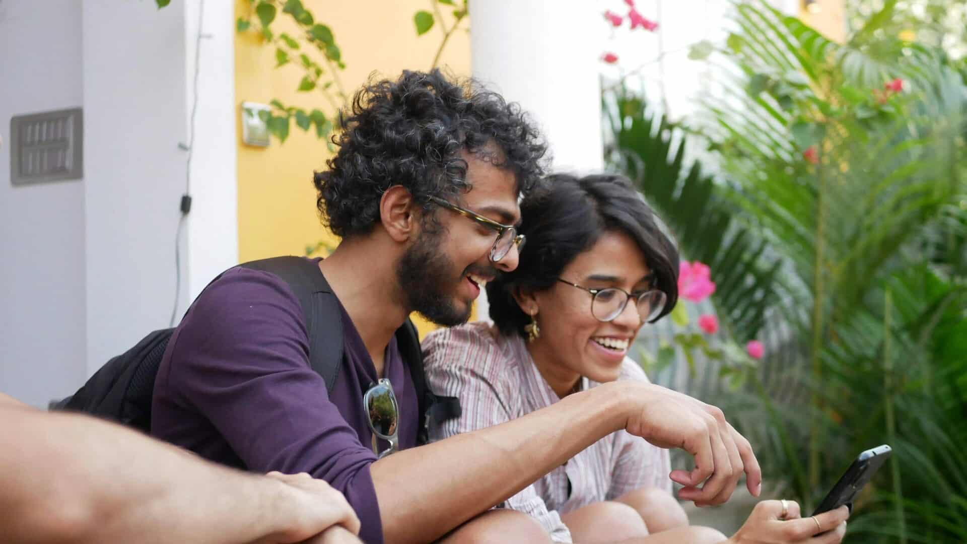 A couple laughing together while looking something at the phone.